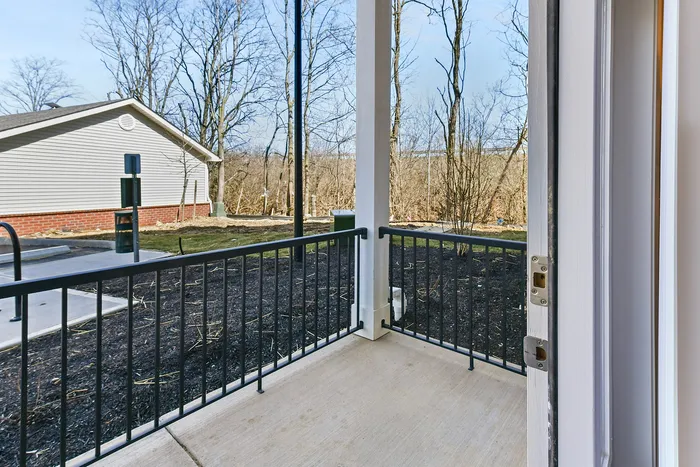 Inviting outdoor patio with a serene view of trees and a charming nearby building, perfect for relaxing moments.