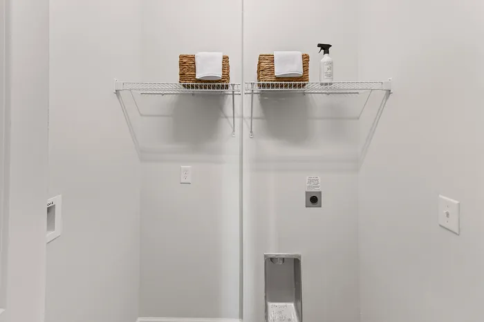Chic laundry nook featuring sleek shelving with wicker baskets, set against a clean, modern backdrop.