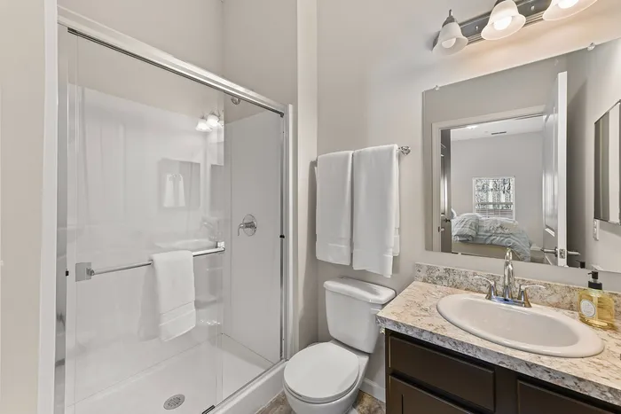 Elegant bathroom featuring a modern glass shower, marble countertop, and stylish lighting.