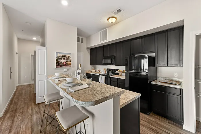 Modern kitchen with sleek black cabinets, elegant countertops, and a cozy breakfast bar with stylish seating.