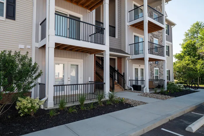Elegant apartment exterior with private balconies and landscaped garden, featuring modern architecture and inviting entryways.