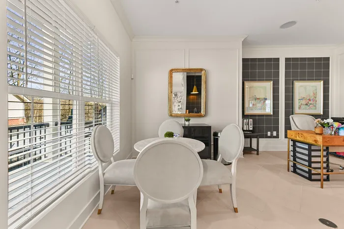 Bright dining room with elegant round table, stylish chairs, and reflective mirror complementing the tasteful decor.
