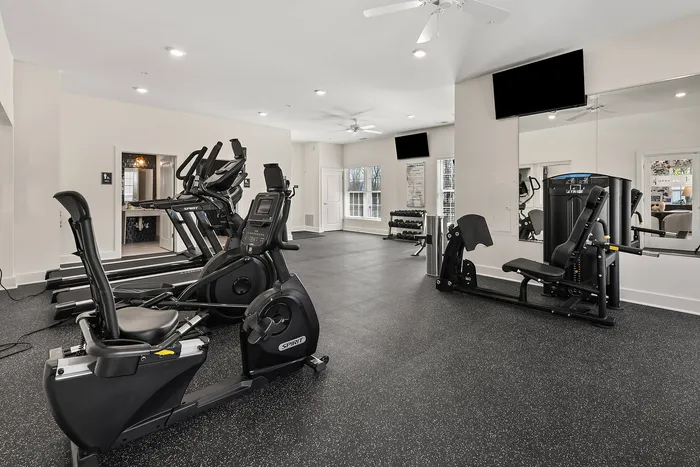 Modern fitness center equipped with state-of-the-art exercise machines, bright lighting, and large windows, creating an invigorating workout atmosphere.