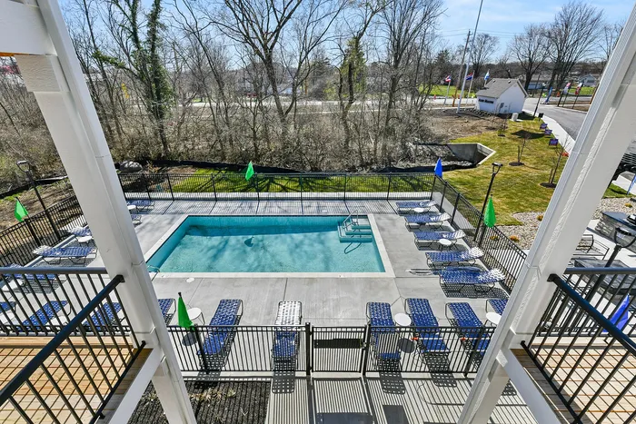 Inviting outdoor pool area with elegant lounge chairs and vibrant flags, surrounded by scenic nature views.