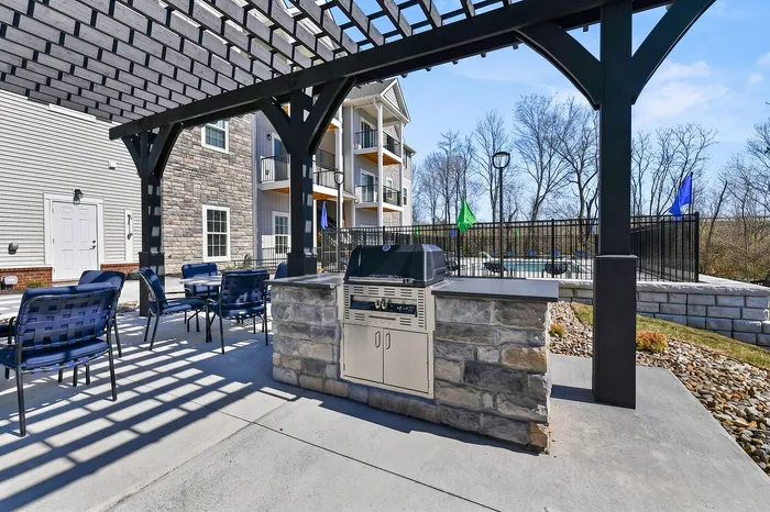 Charming outdoor space featuring a stylish pergola with modern barbecue grill and comfortable seating, perfect for entertaining with scenic views.