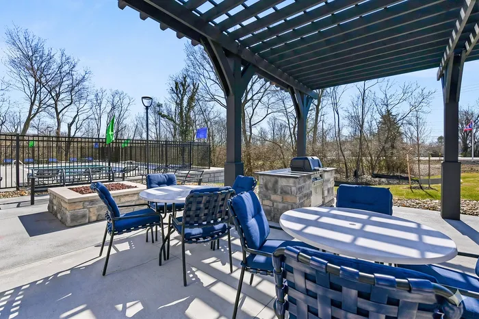Inviting outdoor patio with shaded seating and barbecue area, perfect for relaxing and entertaining by the pool.