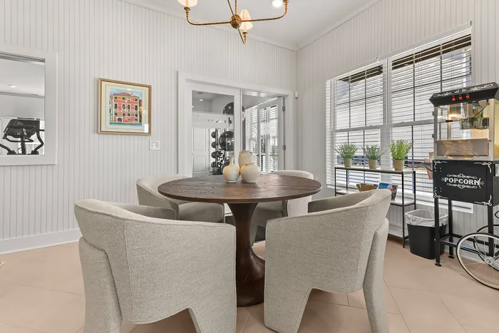 Charming dining area featuring a cozy round table with stylish upholstered chairs, elegant chandelier, and a vintage popcorn machine for a touch of whimsy.