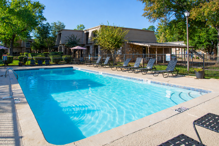 Inviting outdoor pool area with lounge chairs and lush greenery, perfect for relaxation and leisure.