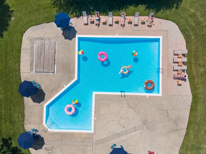 Inviting outdoor swimming pool with vibrant inflatables, surrounded by sun loungers and umbrellas, perfect for relaxation and fun.
