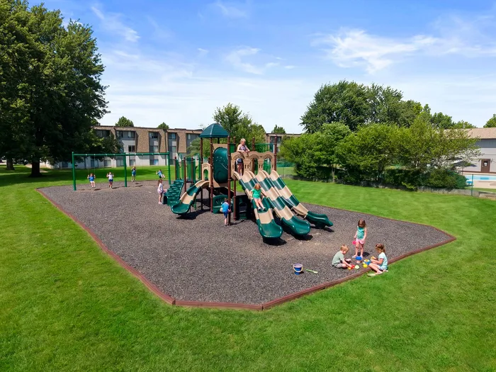 Vibrant playground set amidst lush green lawns with children enjoying slides and swings, perfect for family-friendly living.