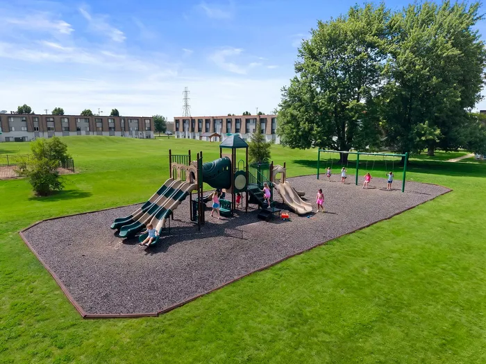 Charming community playground surrounded by lush greenery, featuring slides and swings, perfect for family enjoyment.