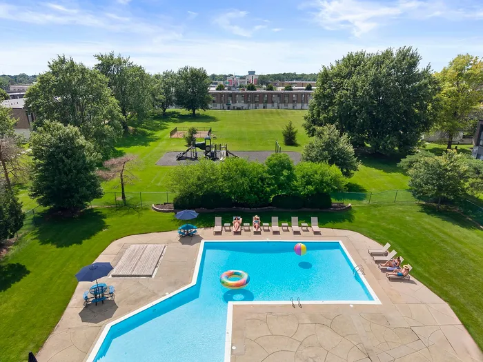 Inviting outdoor pool area with lounge chairs, vibrant umbrellas, and lush green surroundings, perfect for relaxation and leisure.