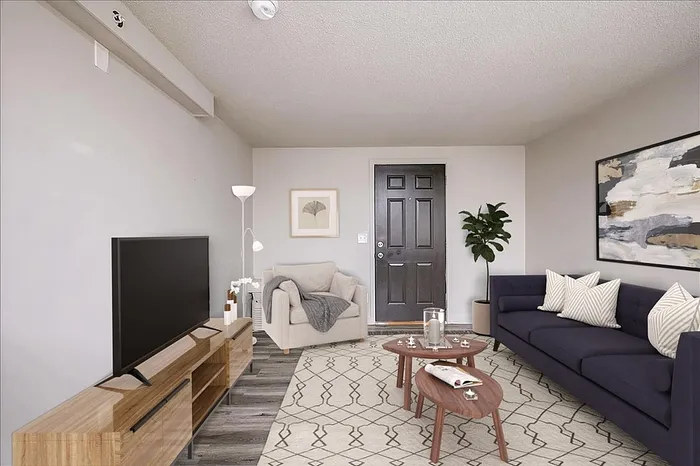 Modern living room with stylish decor, featuring a sleek navy sofa, cozy armchair, and chic wooden coffee table, enhanced by elegant artwork and vibrant greenery.