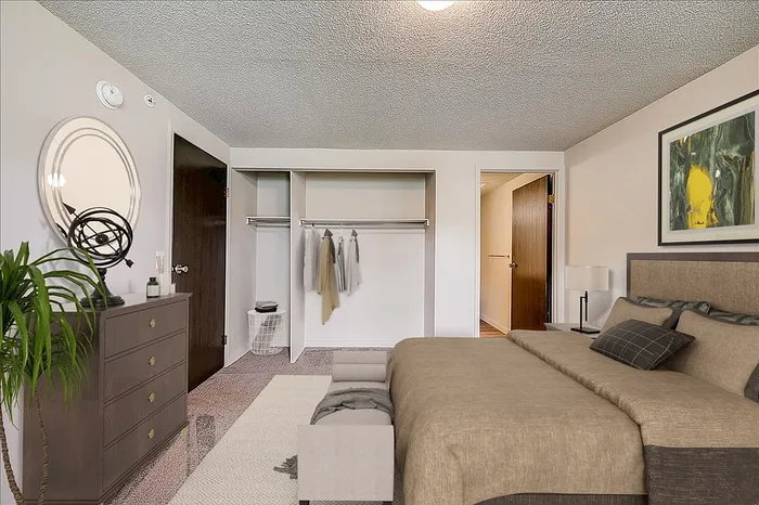 Inviting bedroom with plush carpeting, sleek dresser, and a spacious open wardrobe complemented by modern decor.
