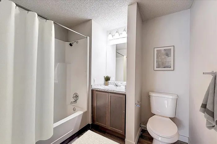 Elegant bathroom featuring a sleek marble countertop, modern fixtures, and a relaxing bathtub with a stylish curtain.