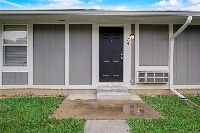 Charming entryway of a modern apartment with a sleek black door and inviting front porch.