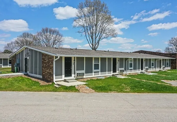 Charming single-story apartments with modern design, set in a peaceful suburban neighborhood with lush green lawns and mature trees.