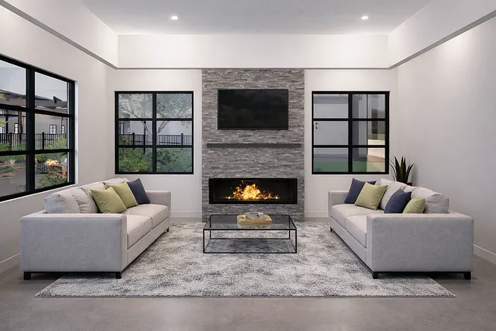 Modern living room with elegant gray sofas, cozy fireplace, and large windows offering natural light and scenic views.