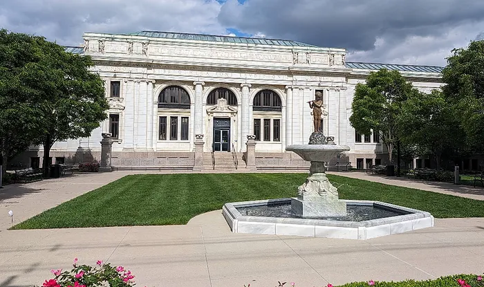 Majestic historic building with ornate architecture and a beautiful fountain set in a lush, green courtyard.