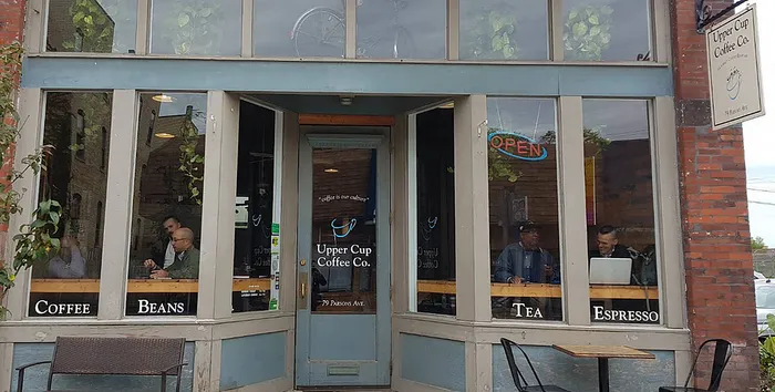Charming local coffee shop with large windows, inviting atmosphere, and patrons enjoying their drinks.