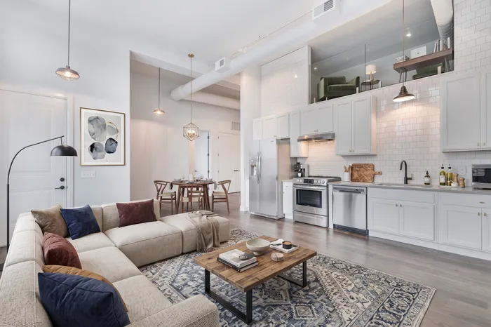 Sophisticated open-plan living space featuring a modern kitchen with stainless steel appliances, cozy sectional sofa, and a chic dining area under elegant pendant lighting.