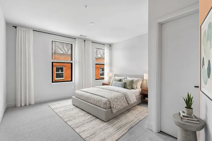 Bright, contemporary bedroom with large windows, elegant neutral decor, and cozy bedding in a stylish apartment.