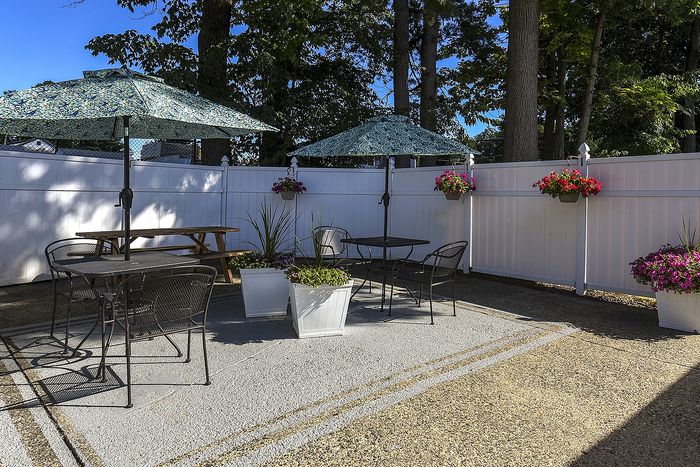 2 tables with chairs and umbrellas in the pool area.