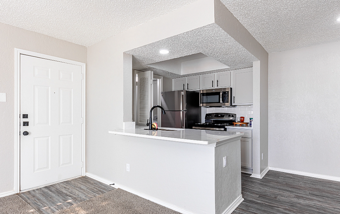 A1 Floor Plan Contemporary kitchen with stainless steel appliances, white cabinetry, and a stylish breakfast bar.