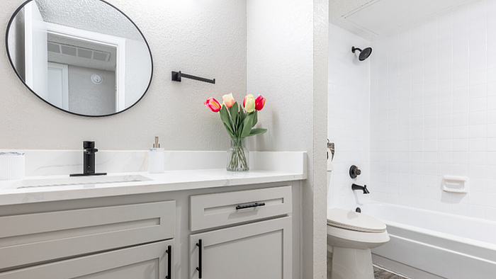 A1 floor plan bathroom with modern vanity, round mirror, and tulip arrangement for a refreshing touch.