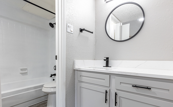 B1 Floor plan Designer Contemporary bathroom featuring a round mirror, elegant vanity, and pristine bathtub.