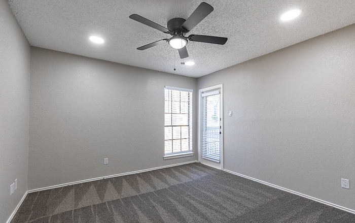 B1 floor plan Designer primary bedroom with modern ceiling fan and large window offering natural light.