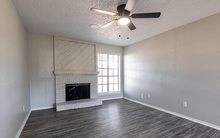 B1 Floor Plan, Designer living room featuring a stylish fireplace, ceiling fan, and large window for natural light.
