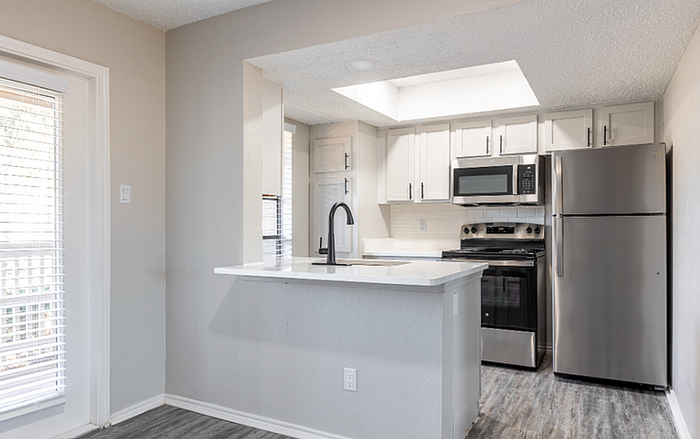 B1 Floor plan Sleek modern kitchen with stainless steel appliances and white cabinetry.