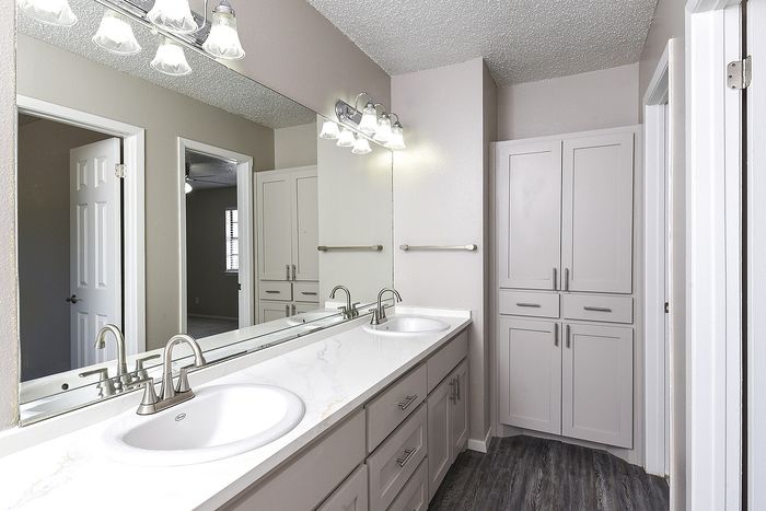 Modern bathroom with dual sinks, large mirror, and sleek cabinetry.