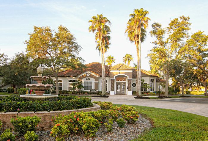 Charming residential entrance with a grand fountain surrounded by lush greenery and tall palm trees, perfect for a serene lifestyle.