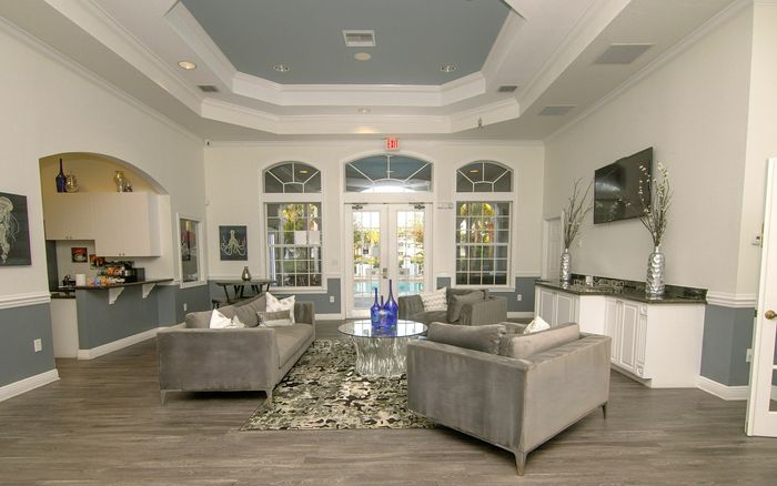 Elegant leasing office with modern decor, featuring plush gray sofas, a chic glass table centerpiece, and large windows opening to a scenic view.