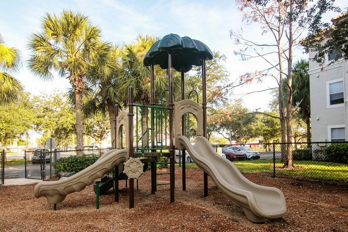 Inviting playground with twin slides surrounded by lush palm trees, offering a fun retreat for children.