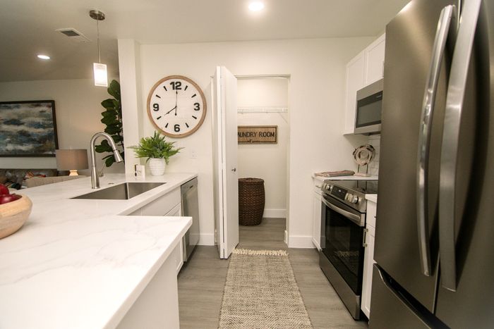 Modern kitchen with sleek stainless steel appliances, elegant white countertops, and a stylish wall clock, creating a bright and inviting atmosphere.