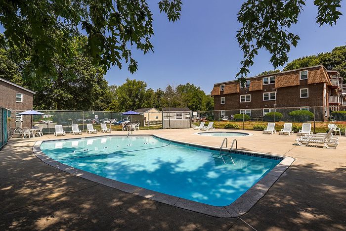 Inviting outdoor pool area with sun loungers and umbrellas, surrounded by lush green trees, perfect for relaxation and enjoyment.