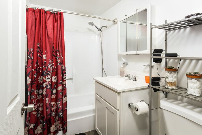 Charming bathroom featuring a vibrant floral shower curtain, white vanity, and sleek shelving with decorative accents.