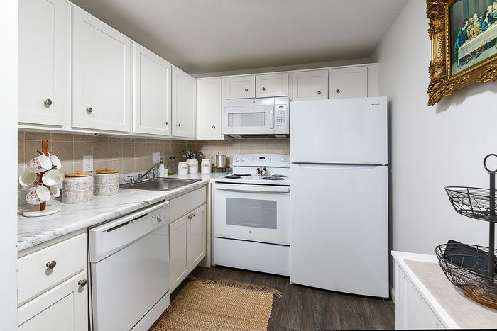 Charming kitchen with white cabinets, white appliances, ideal for culinary creativity.