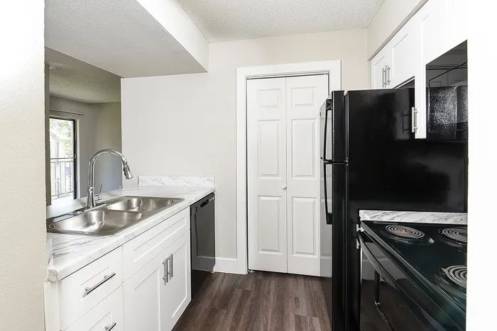 Modern kitchen with sleek black appliances, elegant white cabinetry, and a double stainless steel sink, offering a stylish and functional space.