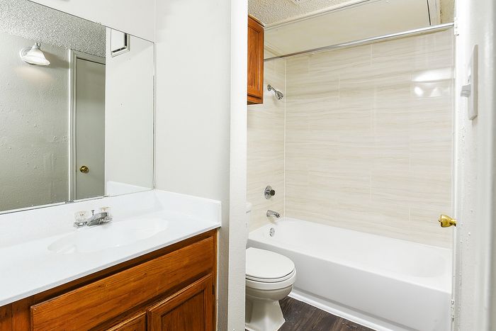 Modern bathroom showcasing elegant wall tiles, stylish wood cabinetry, and a sleek white vanity.