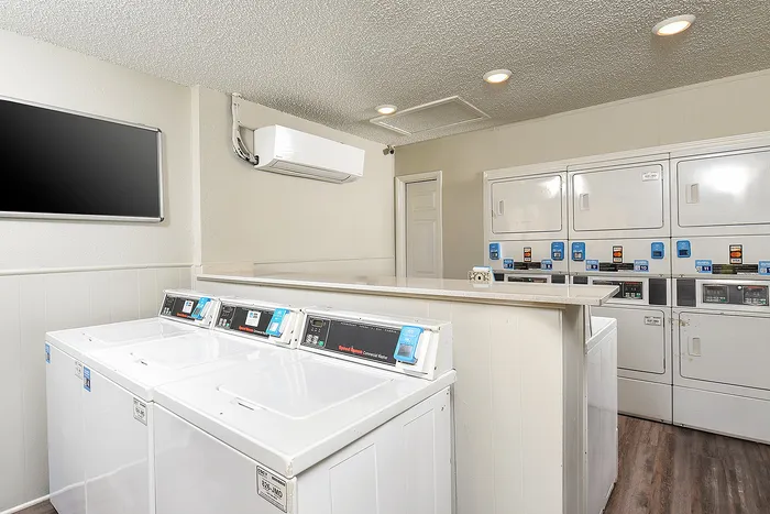 Laundry room with washers and dryers, ample counter space, and bright lighting.