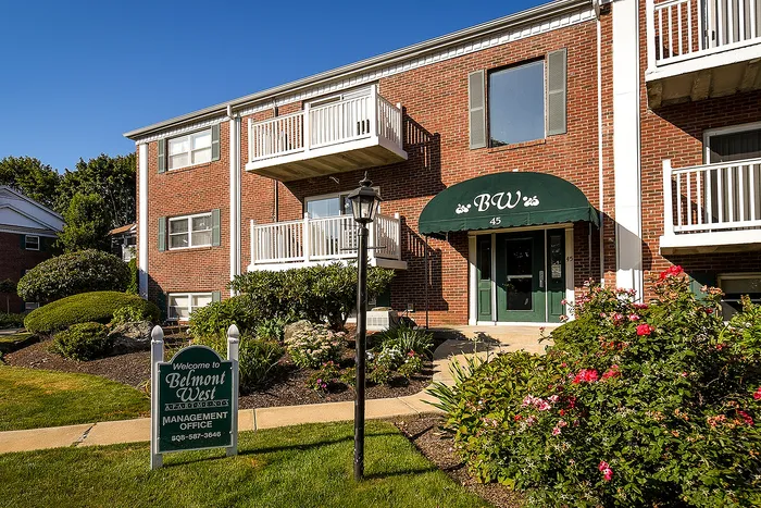 Inviting brick apartment building with charming balconies, lush landscaping, and a welcoming entrance at Belmont West.