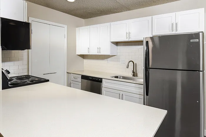 Modern kitchen with sleek stainless steel appliances, elegant white cabinetry, and a spacious countertop.