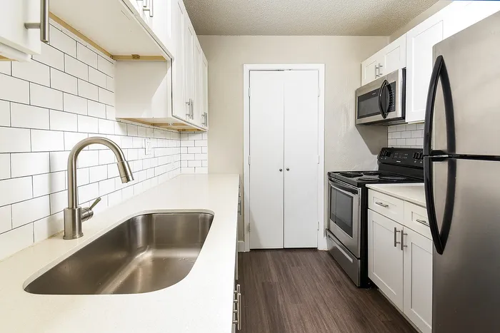 Bright and modern kitchen with sleek stainless steel appliances, elegant white cabinets, and a stylish subway tile backsplash.
