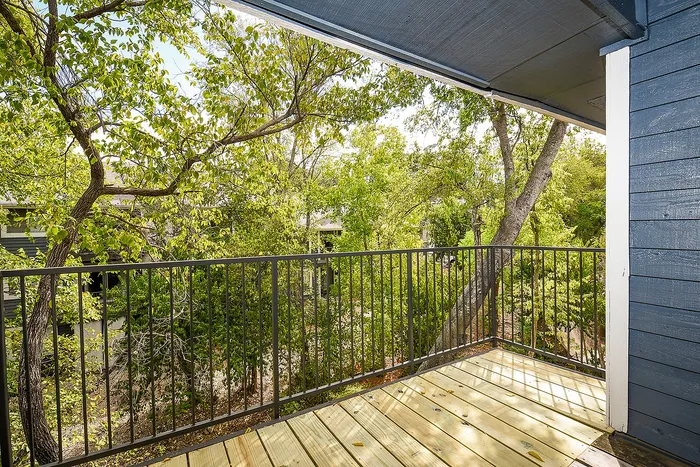 Inviting apartment balcony with wooden decking and scenic views of lush, green treetops, perfect for relaxing outdoors.