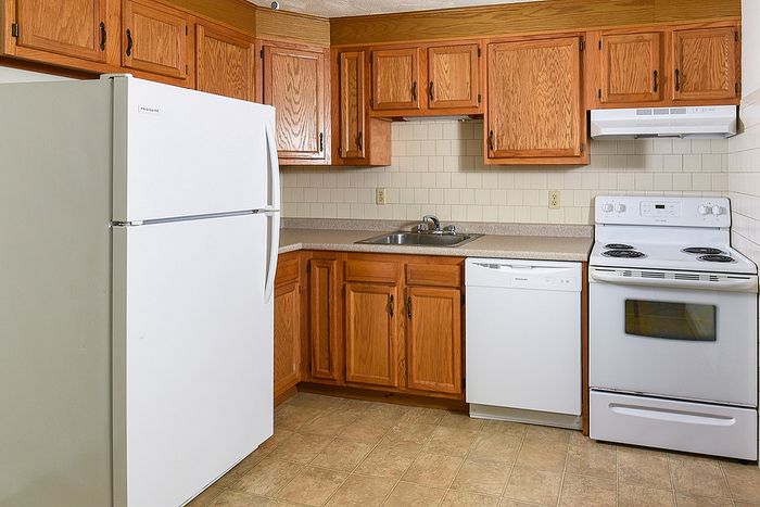 Charming kitchen with warm wood cabinetry, modern appliances, and cozy tiled flooring, perfect for culinary adventures.