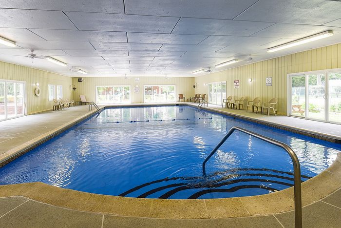 Luxurious indoor swimming pool area with relaxing lounge chairs and bright natural lighting.